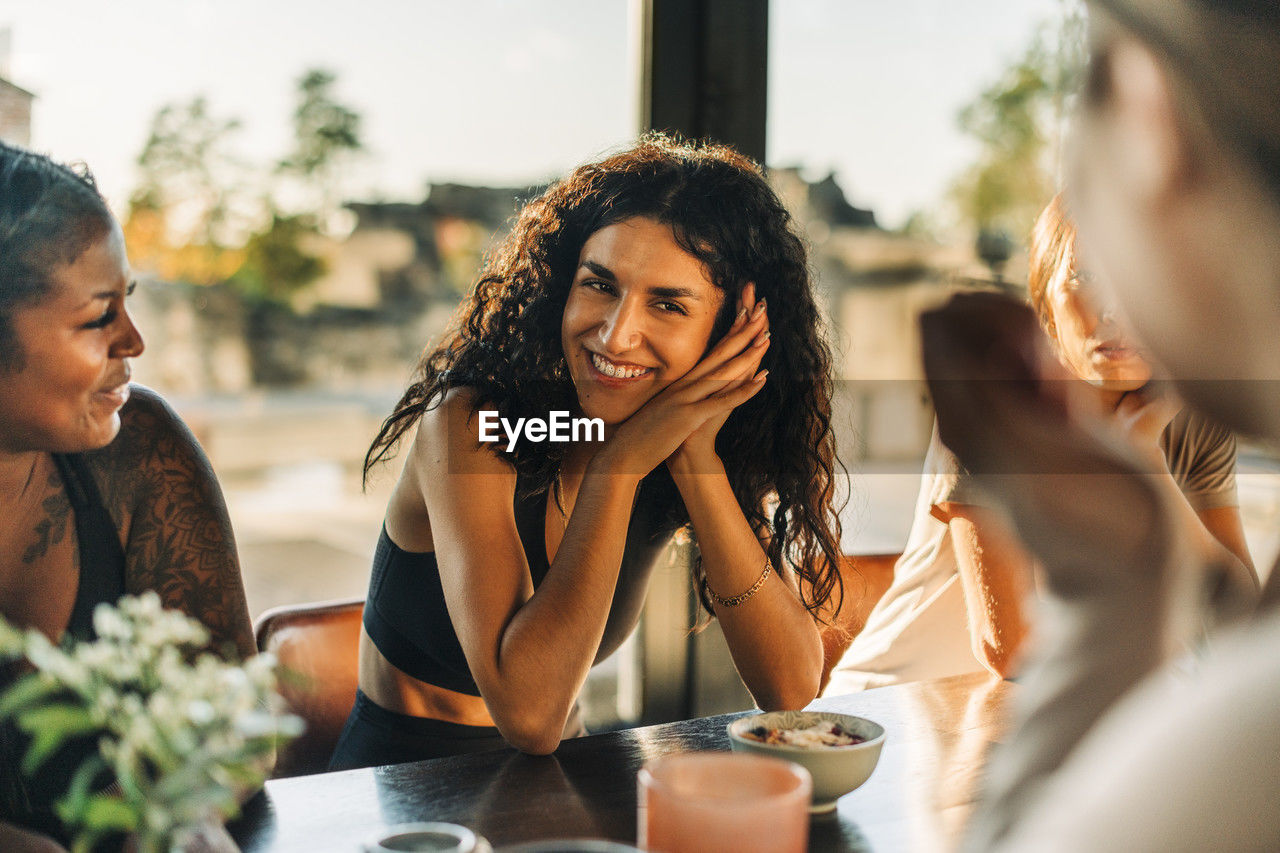 Happy woman leaning on elbows while talking to female friends at retreat center