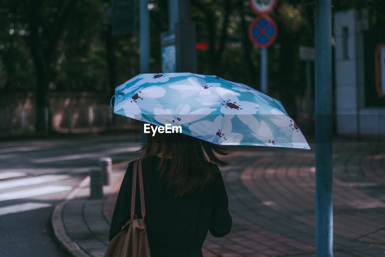 Woman holding umbrella standing on street