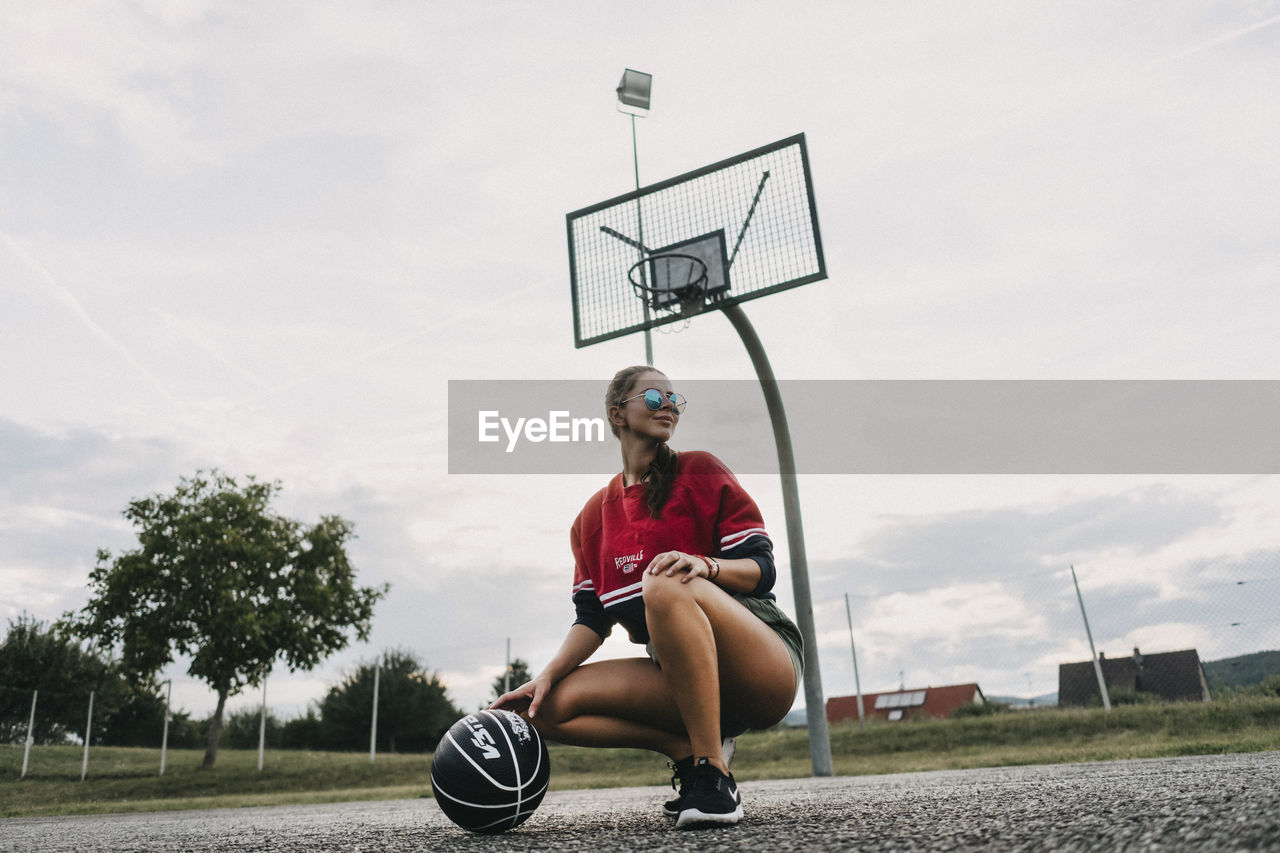 FULL LENGTH OF MAN SITTING ON BASKETBALL COURT