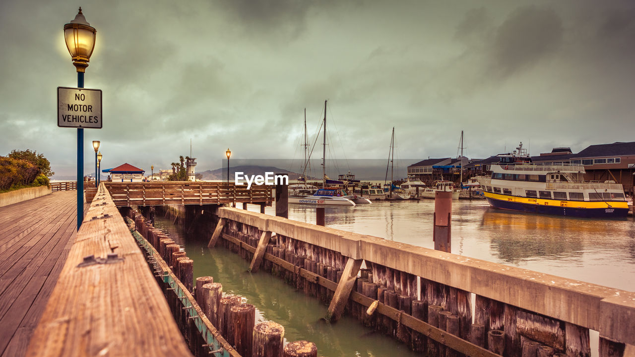 BOATS MOORED AT HARBOR BY SEA AGAINST SKY