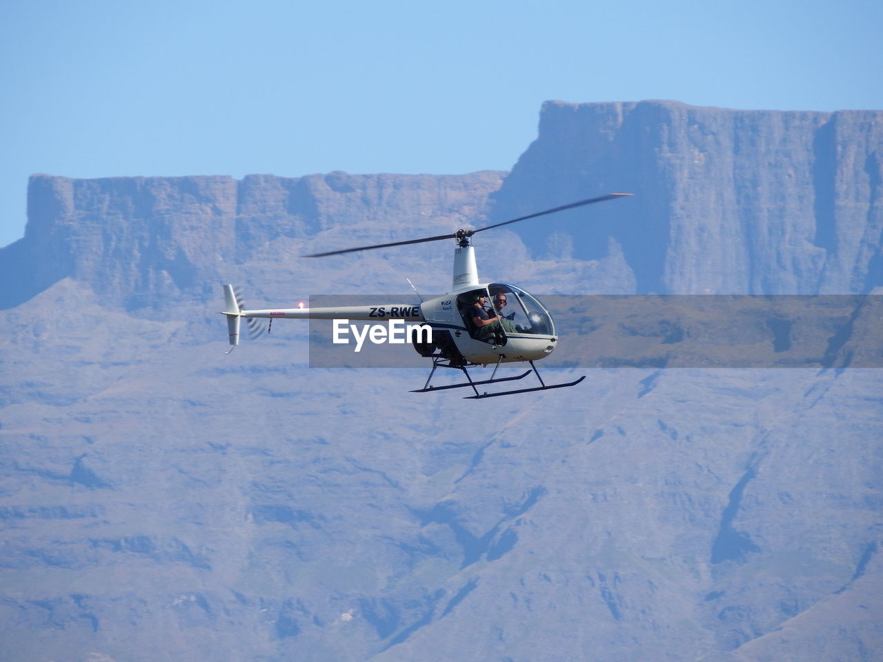 AIRPLANE FLYING ABOVE SNOWCAPPED MOUNTAIN AGAINST SKY