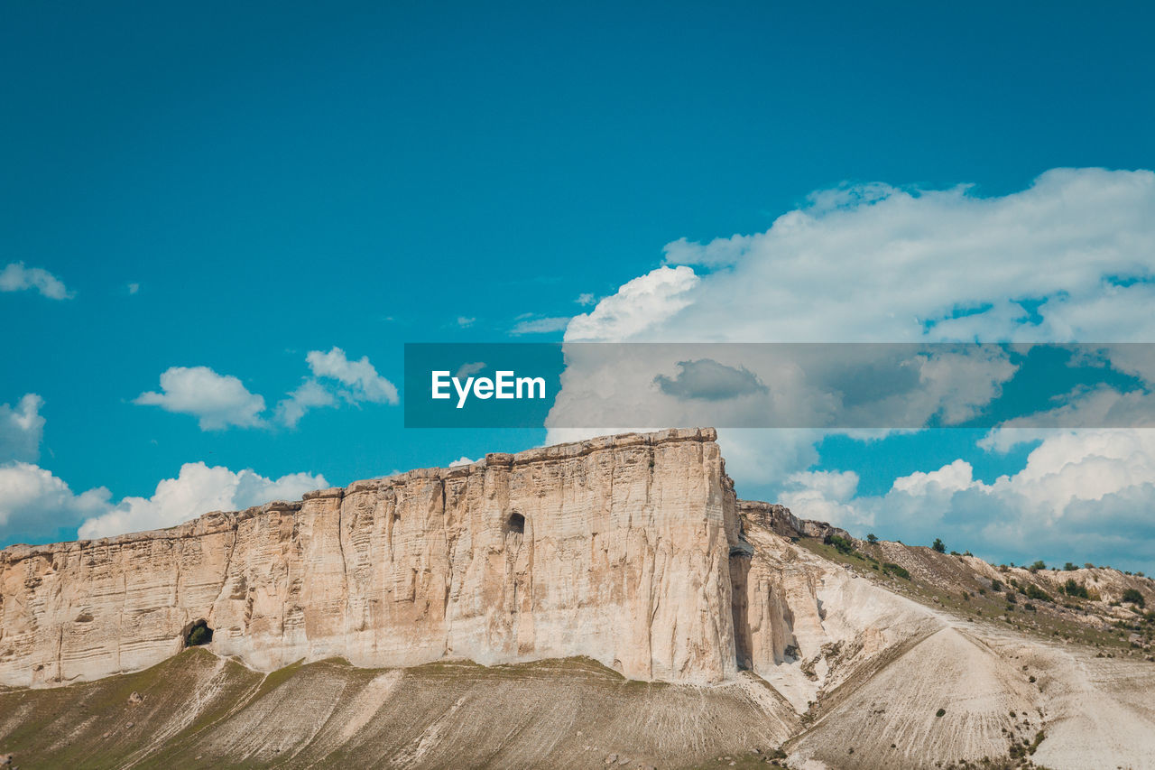 Low angle view of rock formations against cloudy sky