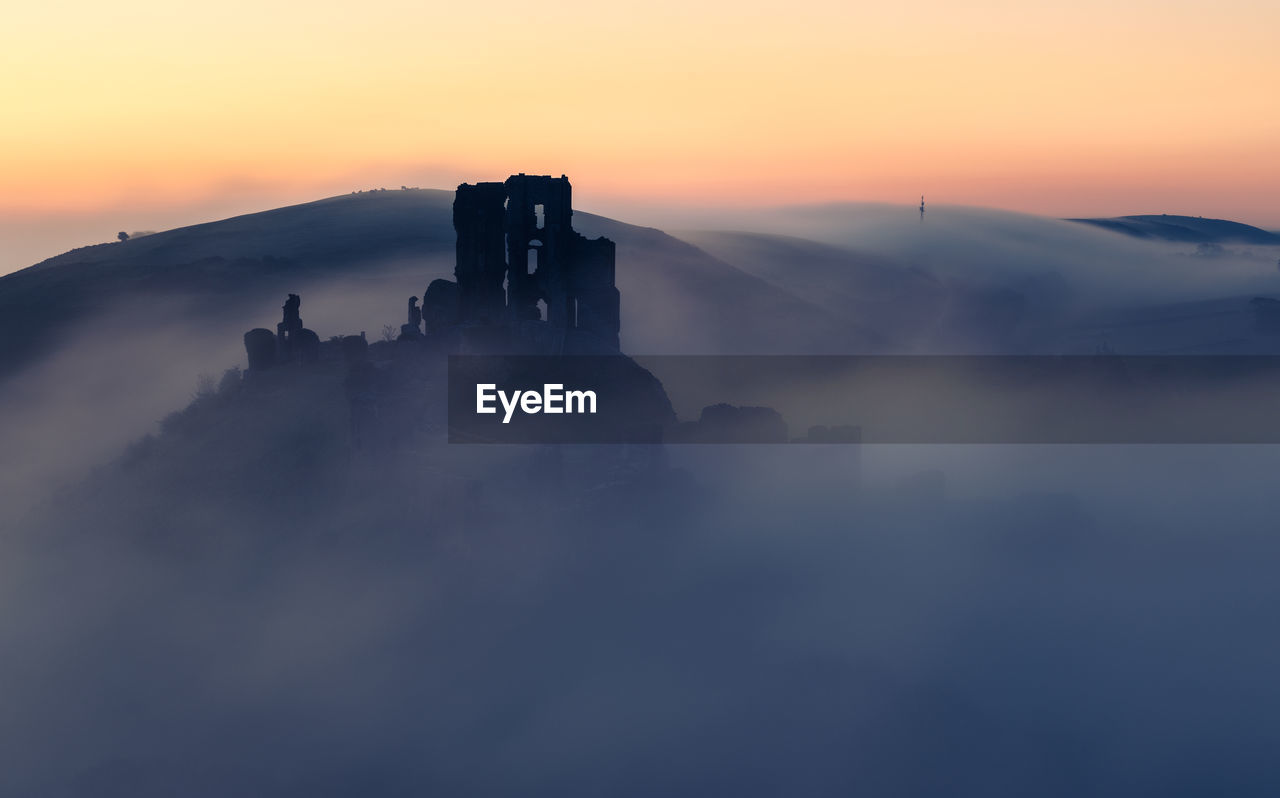 Silhouette of corfe castle against sky during sunrise