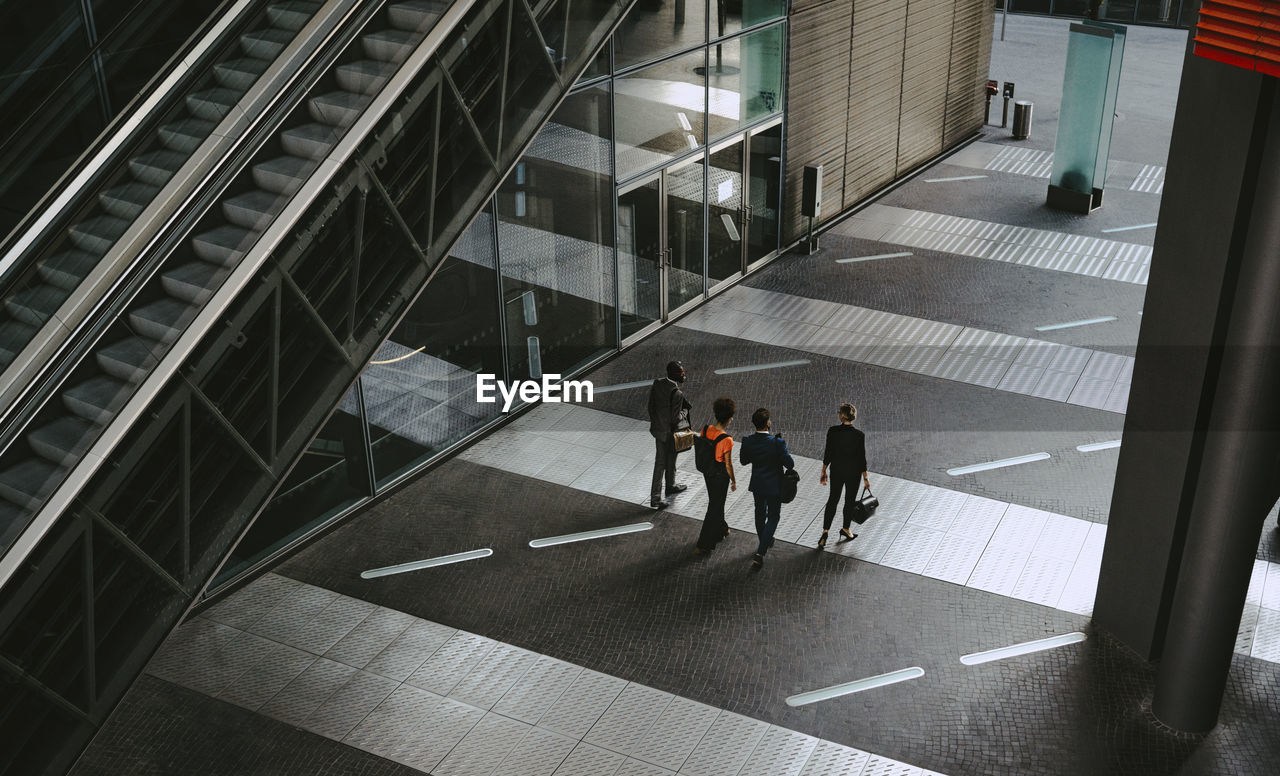 Rear view of female and male coworkers discussing while walking on footpath