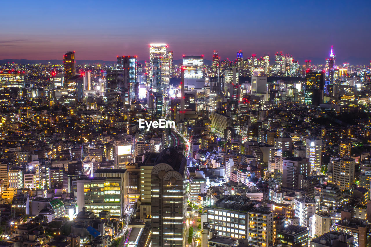 Illuminated cityscape against sky at night