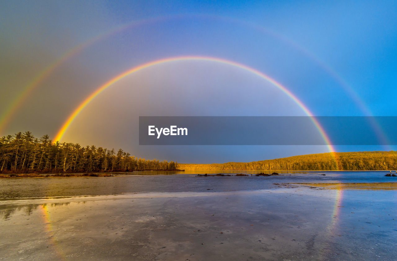 Scenic view of double rainbow with reflection off frozen lake