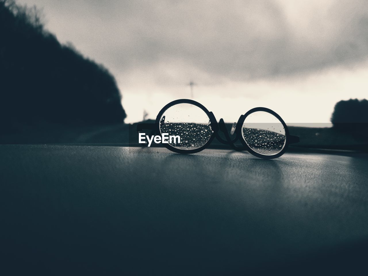 CLOSE-UP OF EYEGLASSES ON GLASS WITH REFLECTION OF WATER