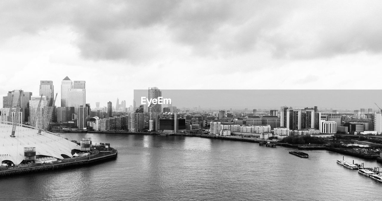 Boats sailing on river in city against sky