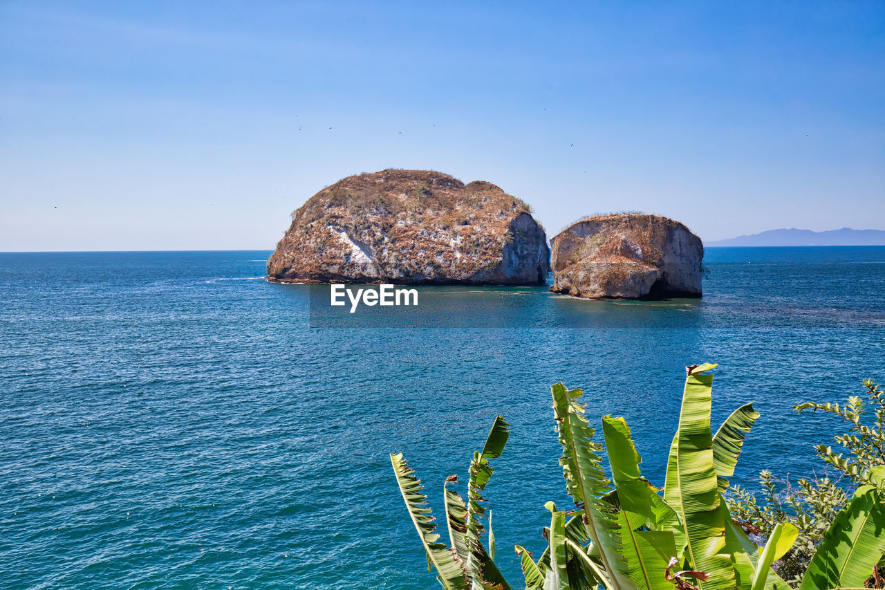 SCENIC VIEW OF ROCK FORMATION IN SEA AGAINST CLEAR BLUE SKY