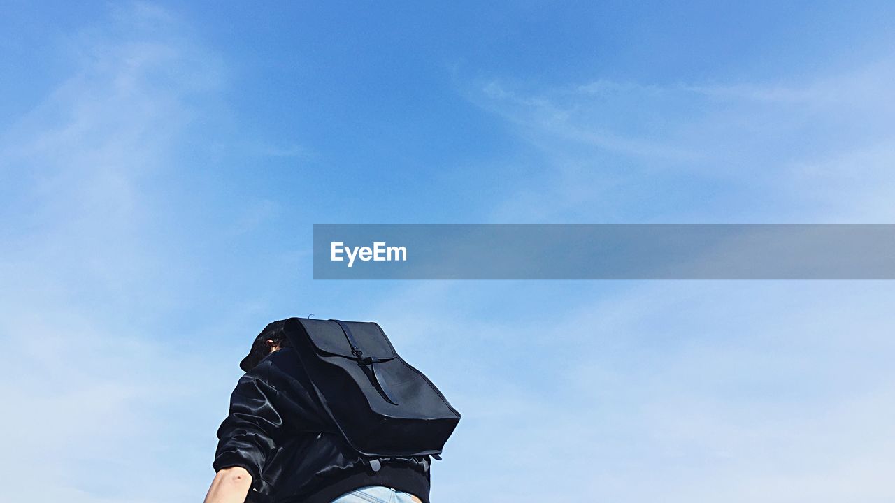 LOW ANGLE VIEW OF PERSON STANDING AGAINST BLUE SKY