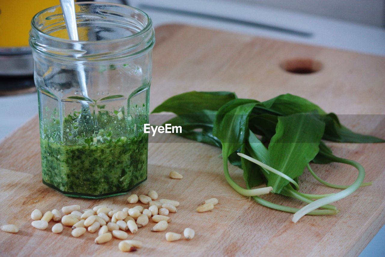 Close-up of pine nuts and ramsons by pesto in jar on cutting board