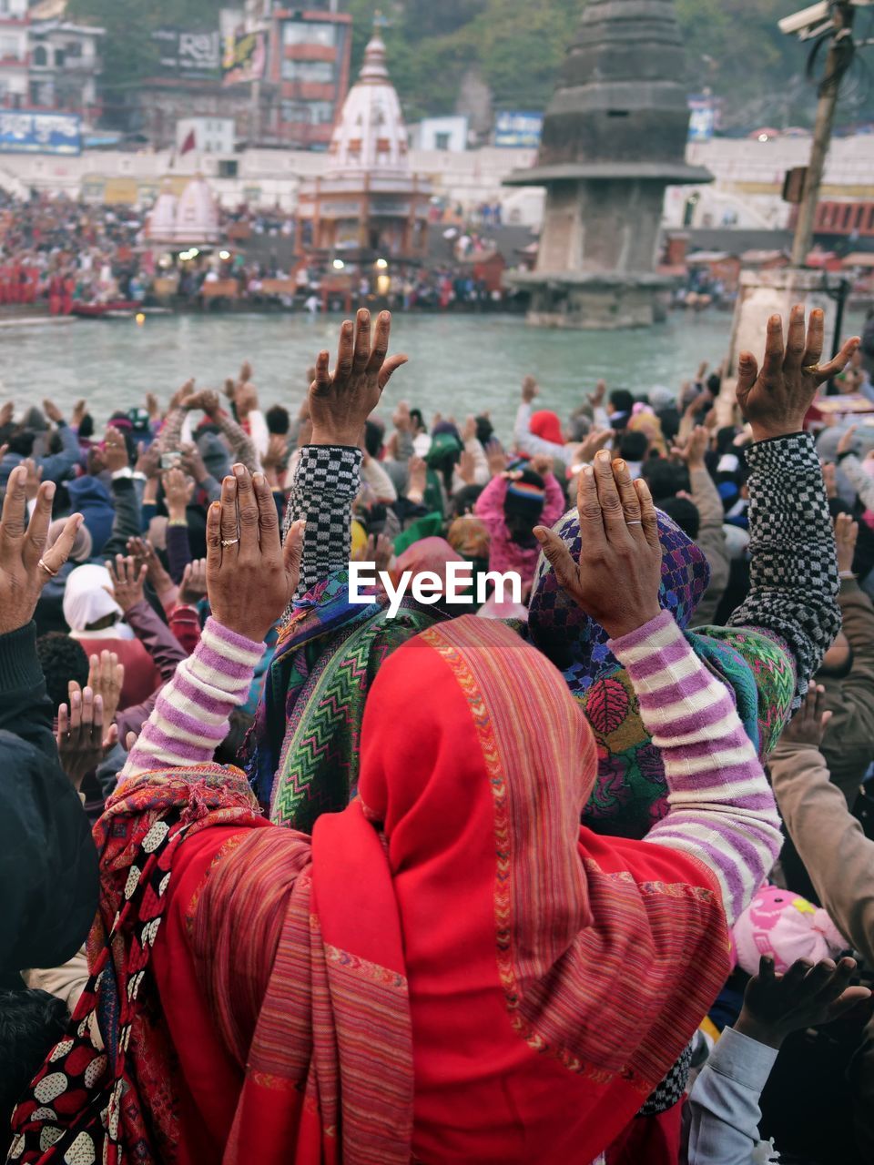 People praying at riverbank in city