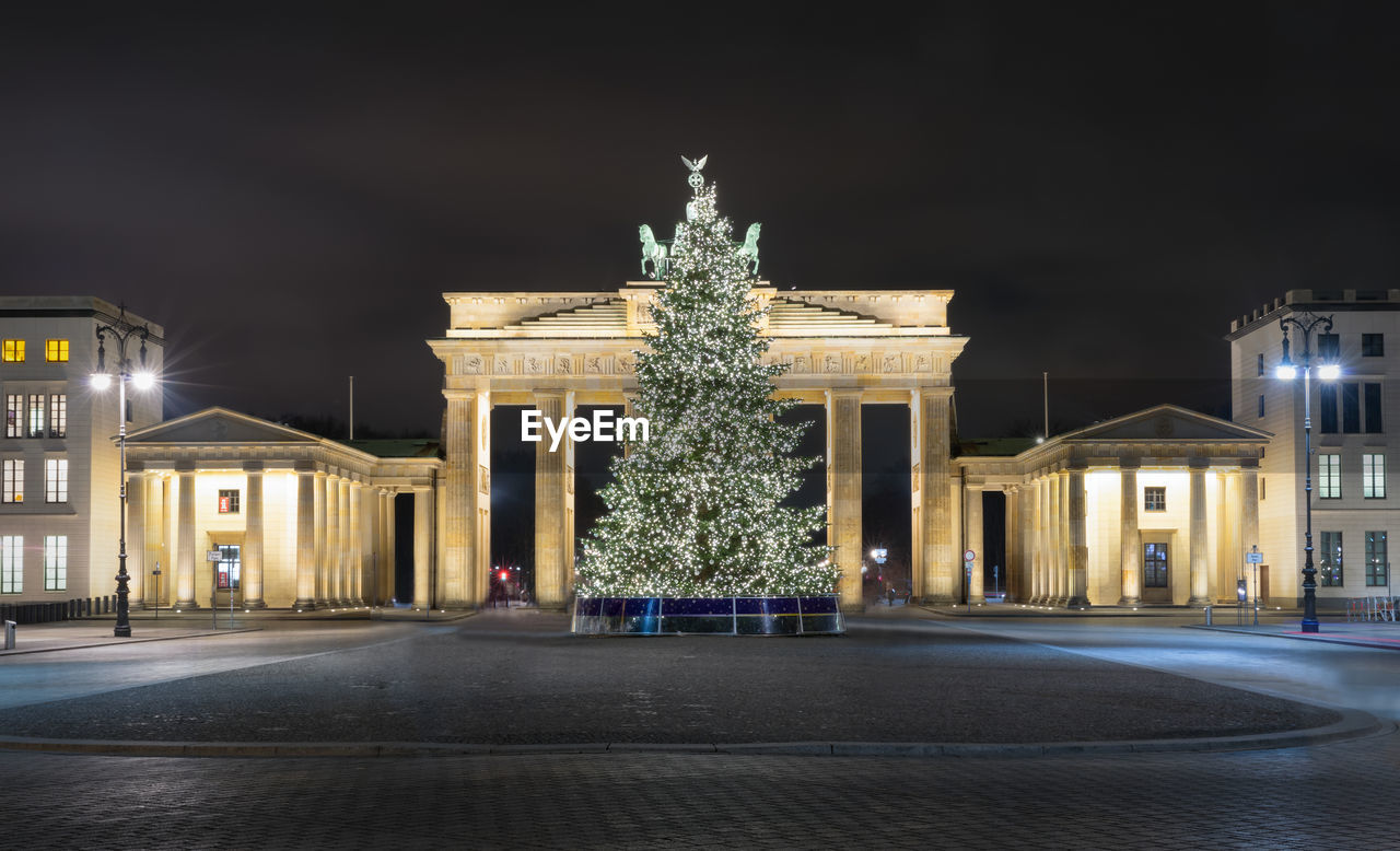 Illuminated christmas tree against brandenburg gate at night