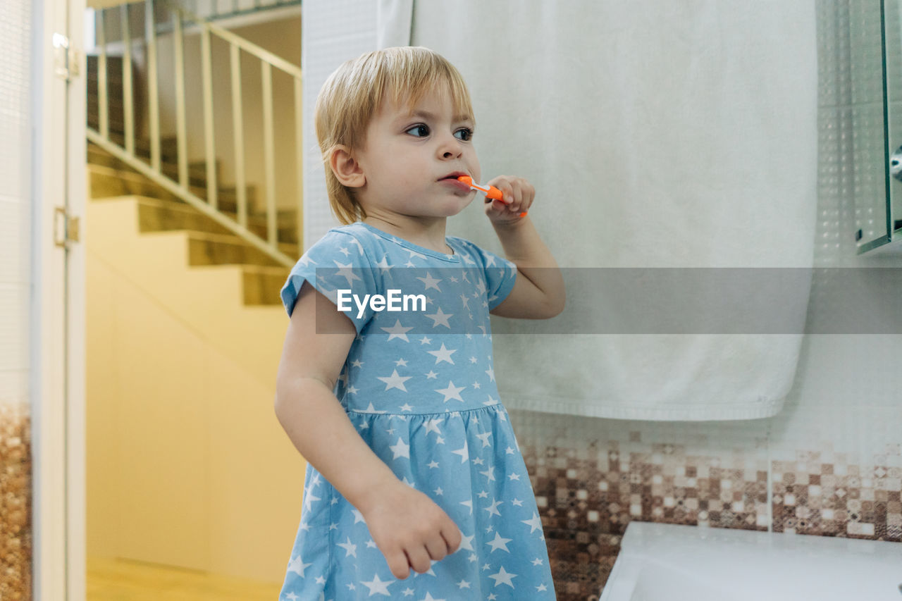 Little toddler girl brushes her teeth in the bathroom.