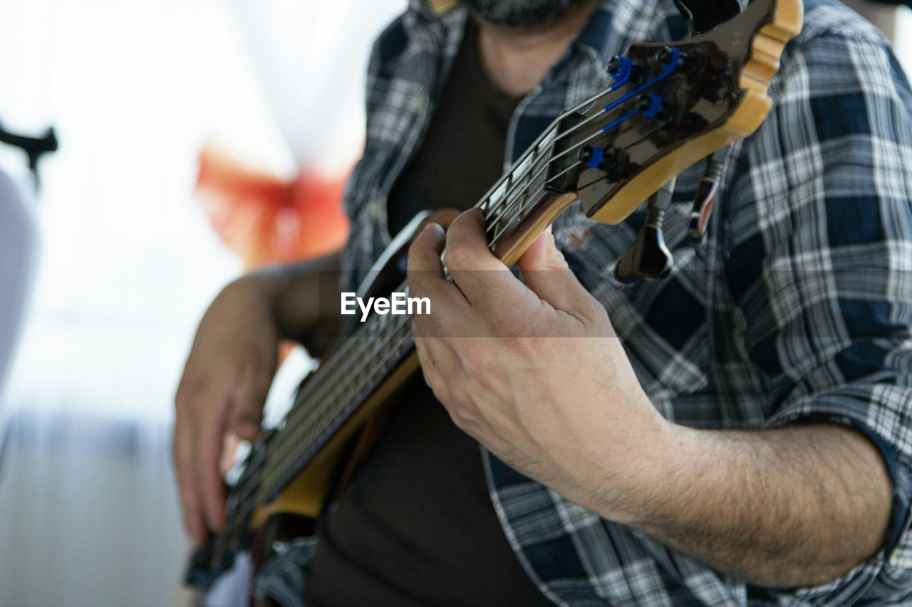 Midsection of man playing guitar