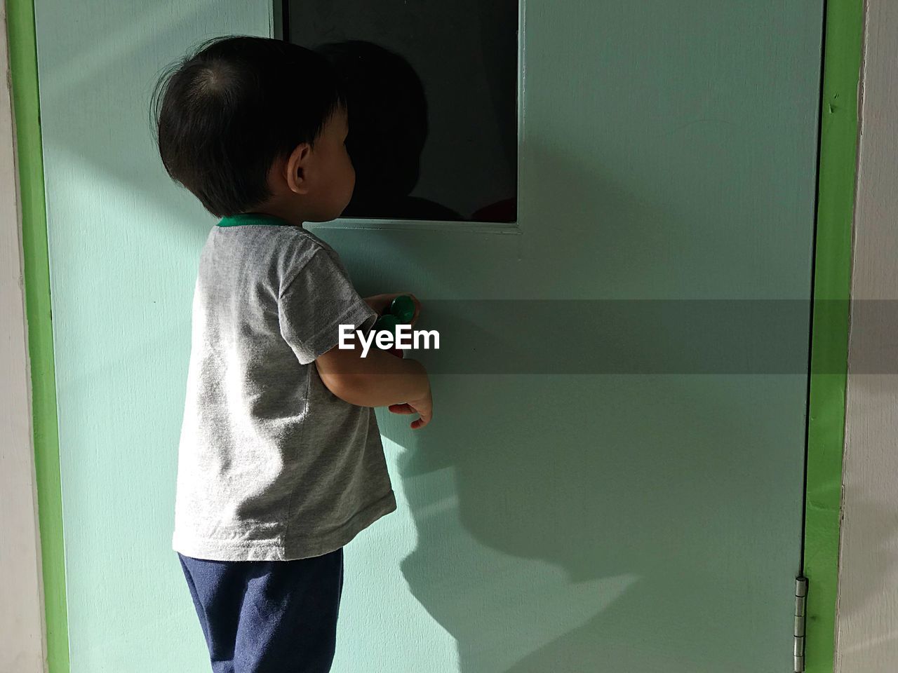 Baby boy peeking in door hole at home