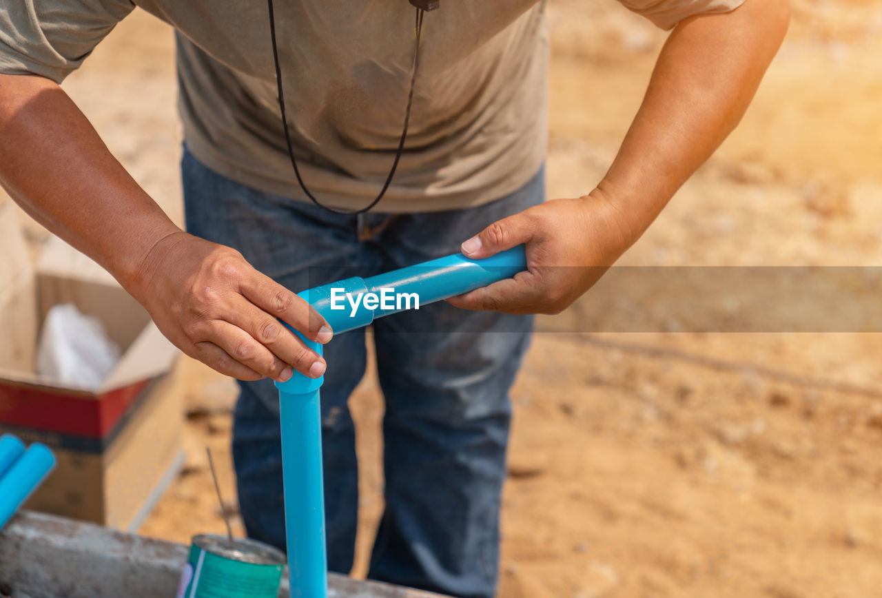 Workers wear pipes that are glued together in plumbing of building.