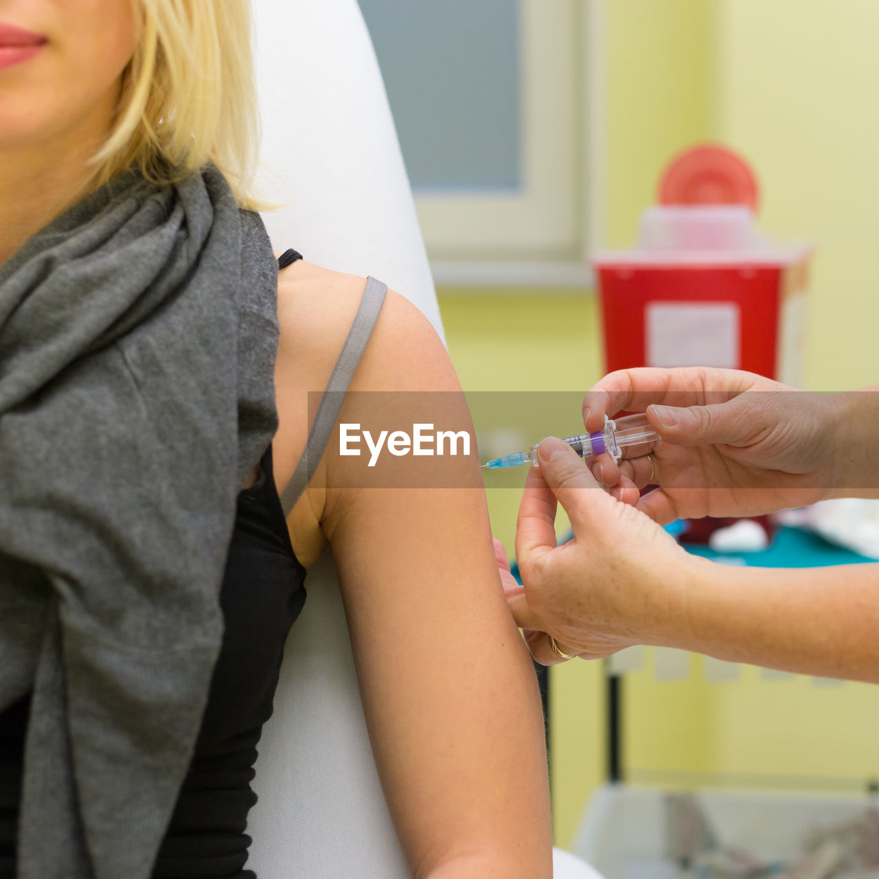 Cropped hand of doctor giving syringe to patient