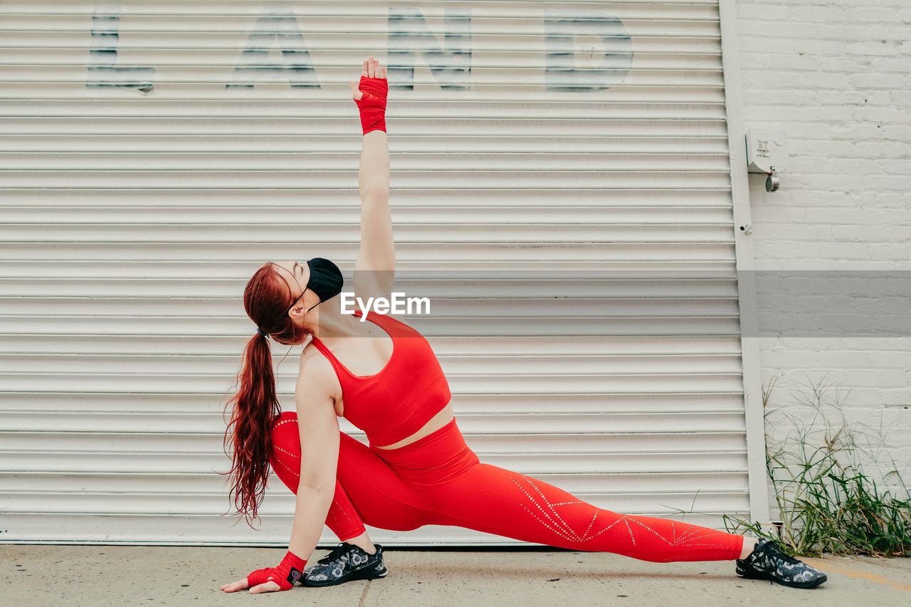 Young female boxer stretching outdoors in brooklyn street.