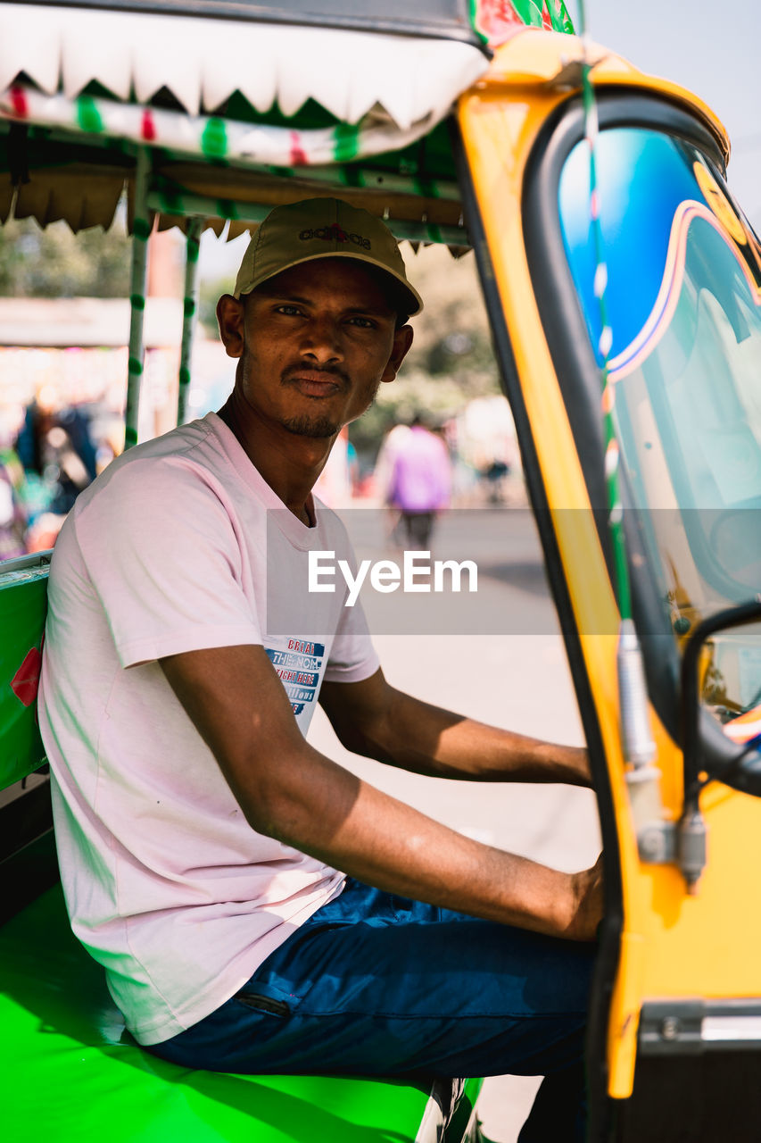 PORTRAIT OF SMILING MAN STANDING ON CAR