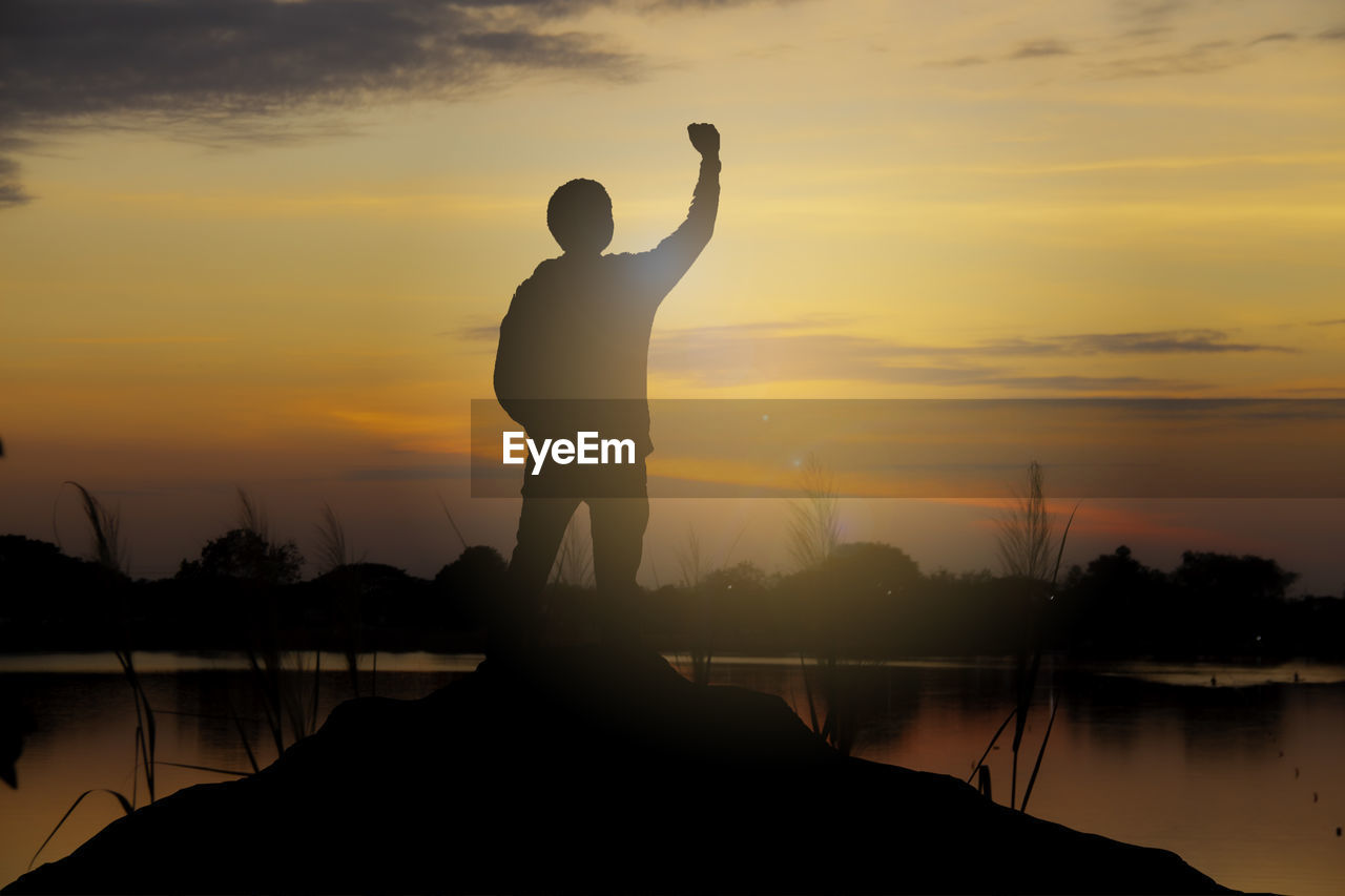 
silhouette of a happy man raised hands up as a successful, victory and achieve a business goal.