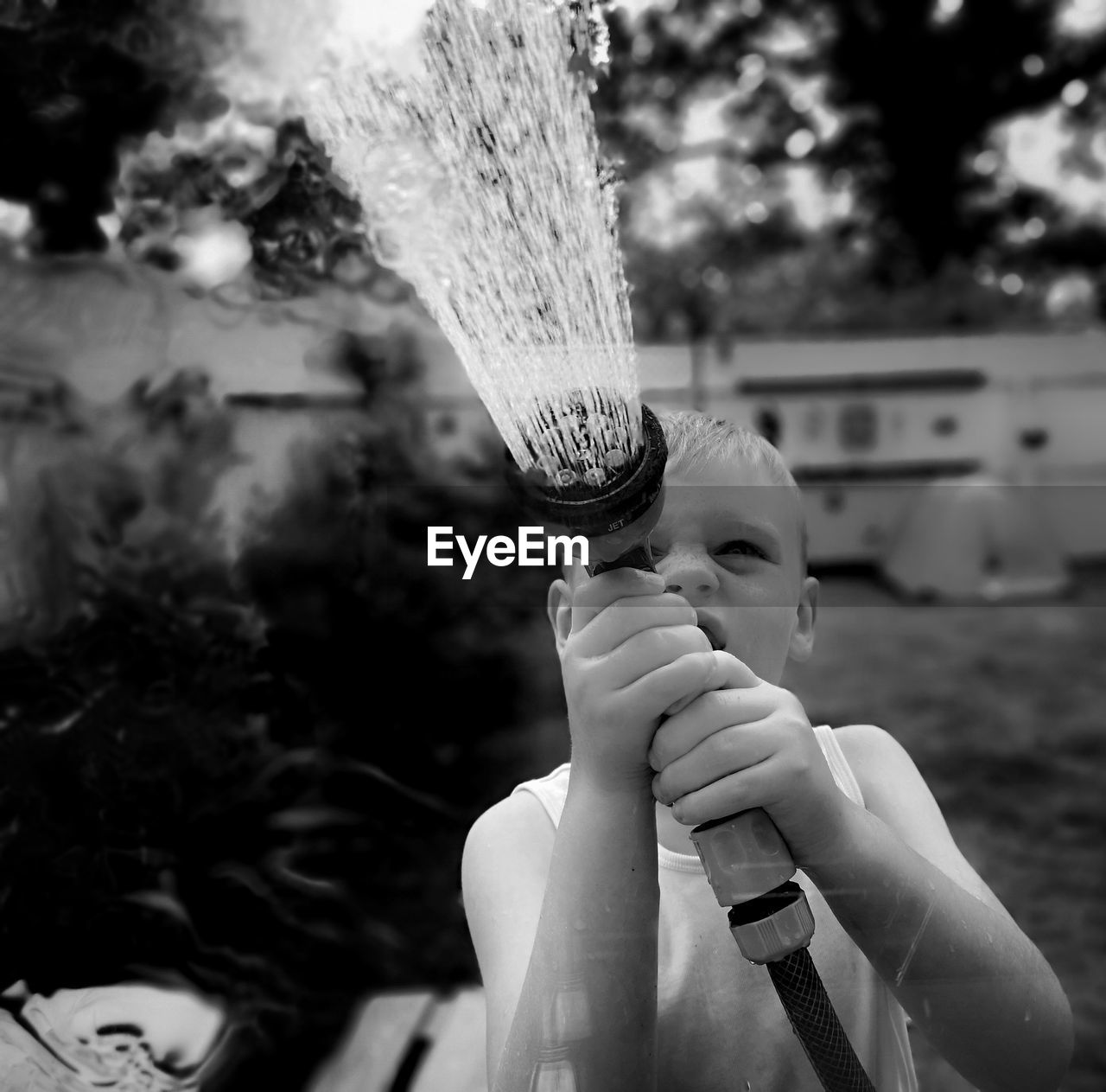 Boy spraying water with garden hose