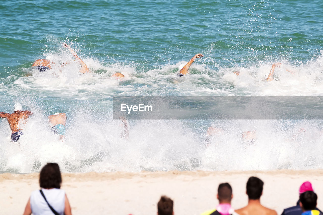 Shirtless men swimming in sea