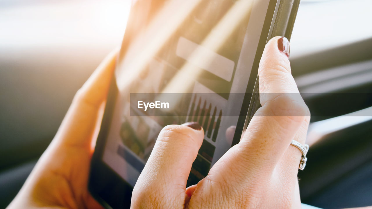 Cropped image of woman using digital tablet in car