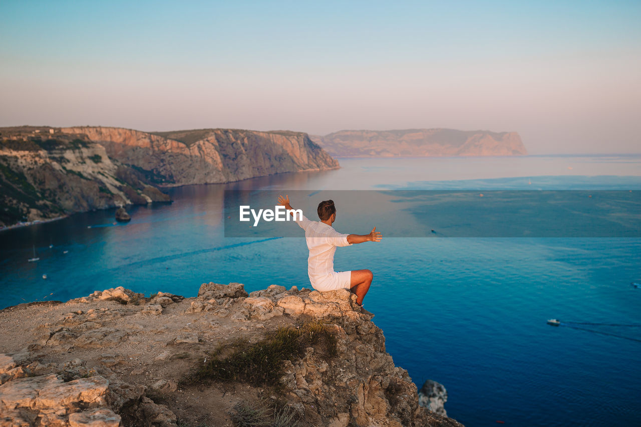 REAR VIEW OF WOMAN LOOKING AT SEA AGAINST SKY