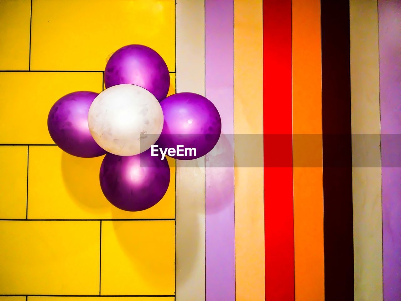 CLOSE-UP OF MULTI COLORED BALLOONS ON YELLOW