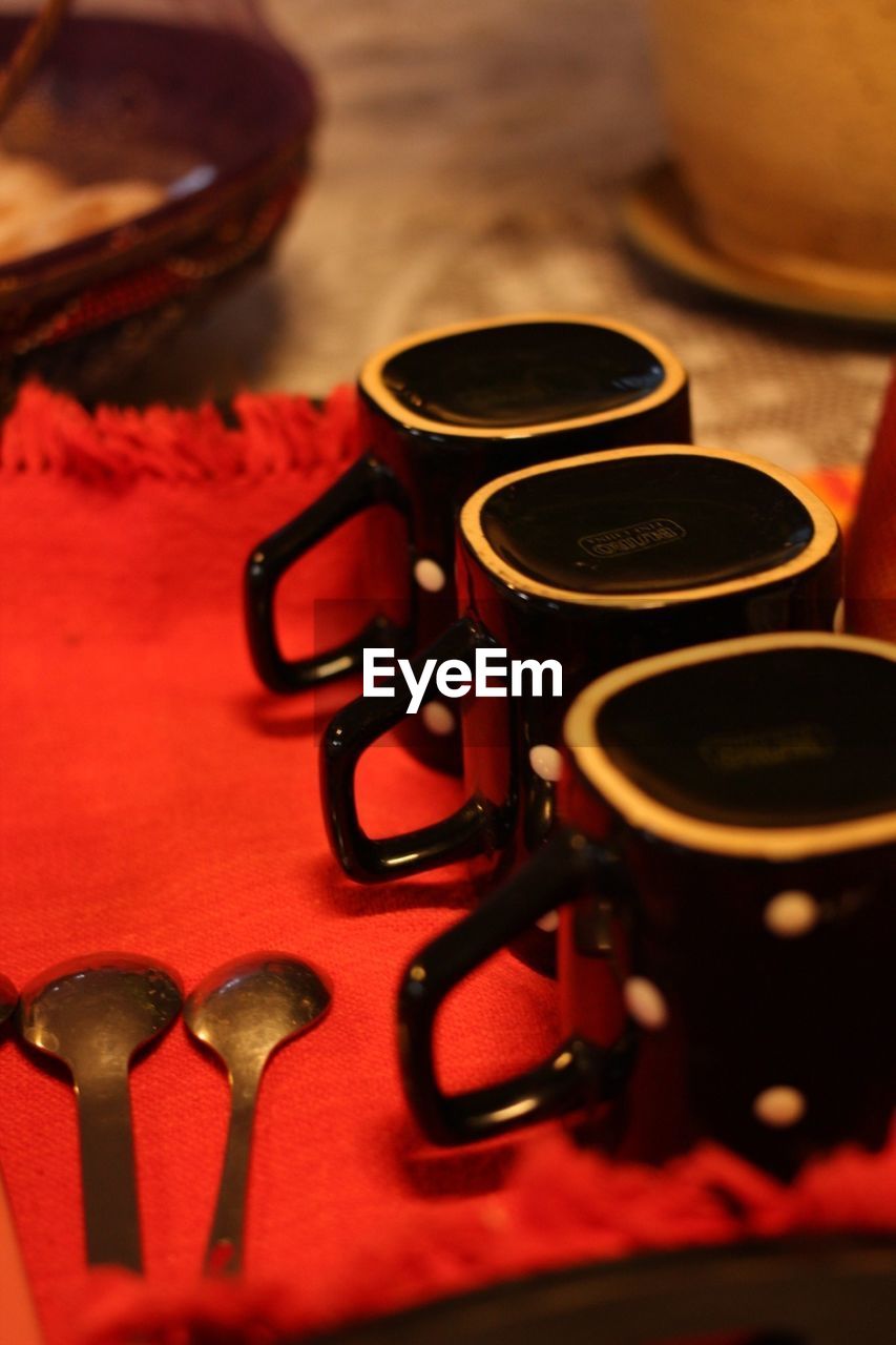 Mugs and spoons on red cloth