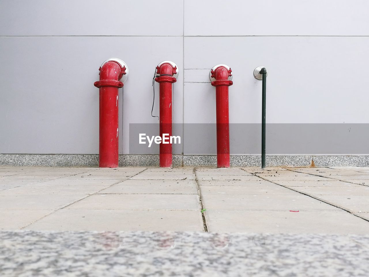 Footpath against red pipes on wall