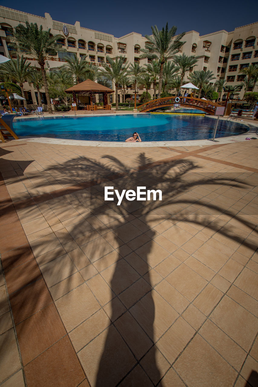 SHADOW OF PERSON ON SWIMMING POOL IN CITY