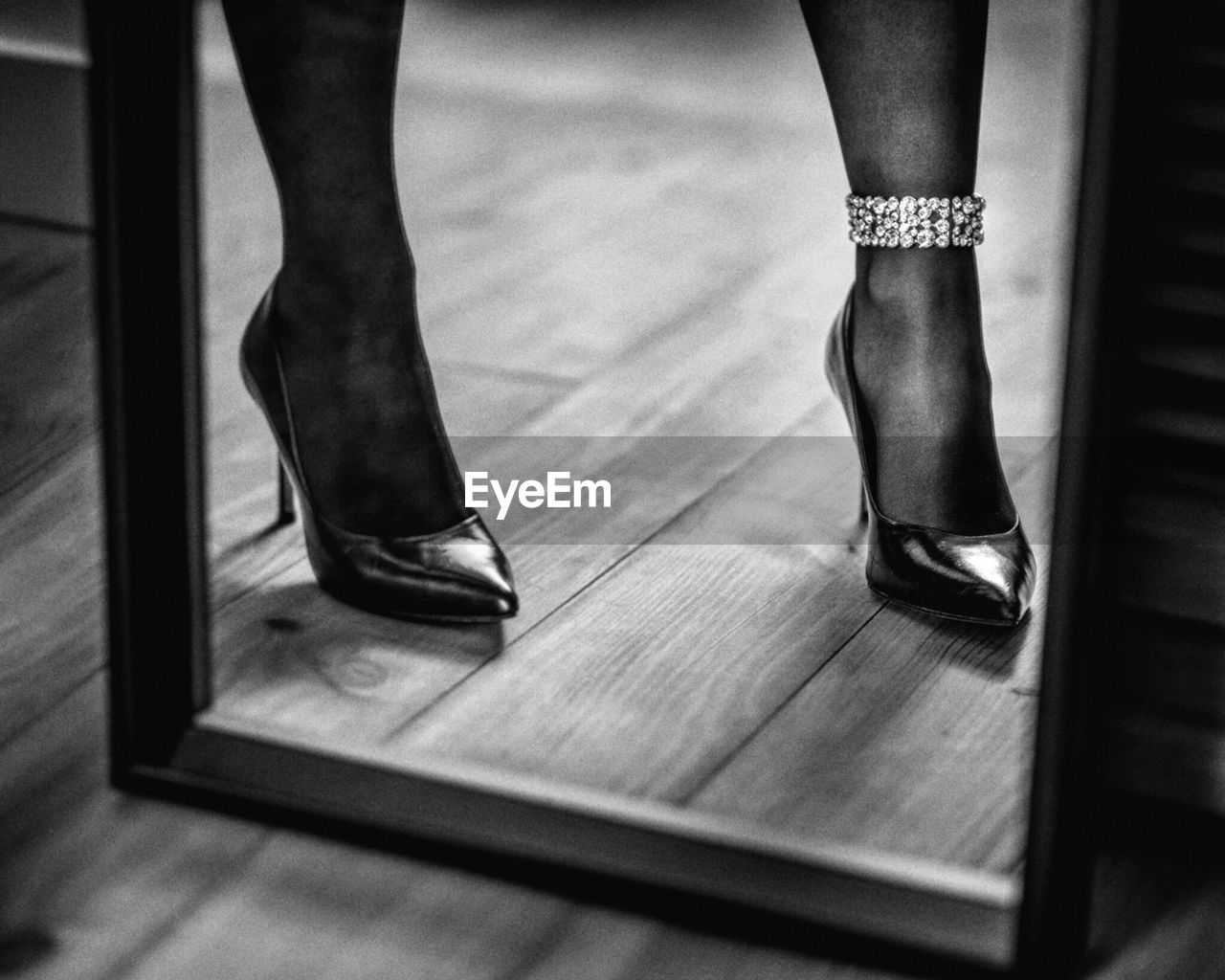 Low section of woman wearing high heels reflecting on mirror