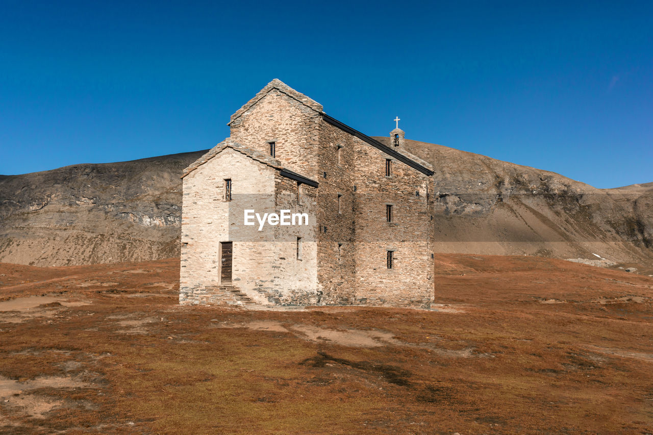 Old church on landscape against clear blue sky