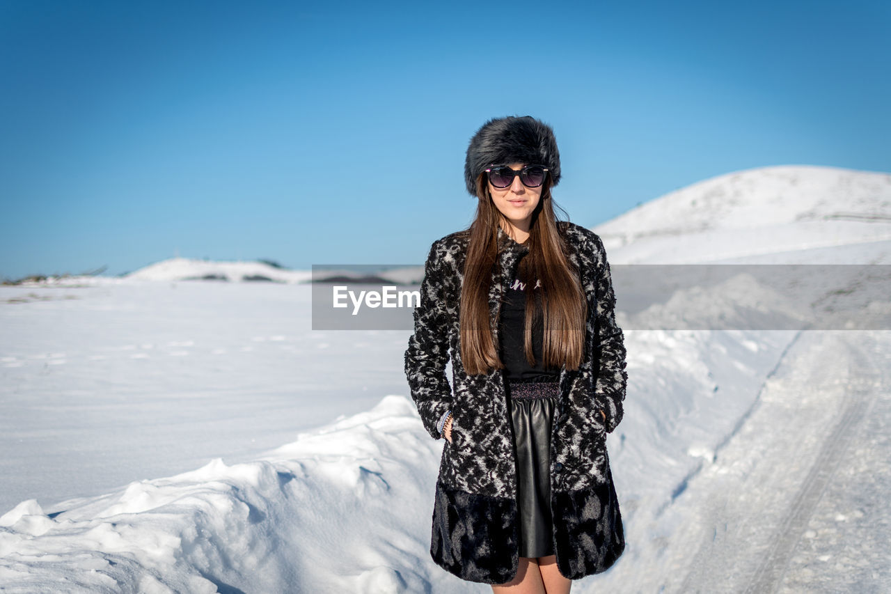 Portrait of woman standing on snow covered land