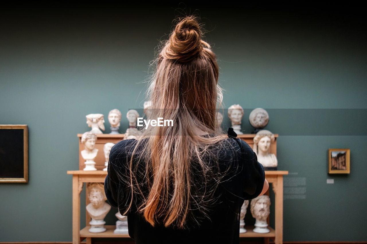 Woman with long hair standing in front of sculptures