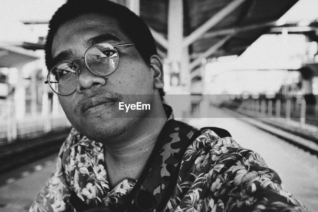 Portrait of man wearing eyeglasses at railroad station