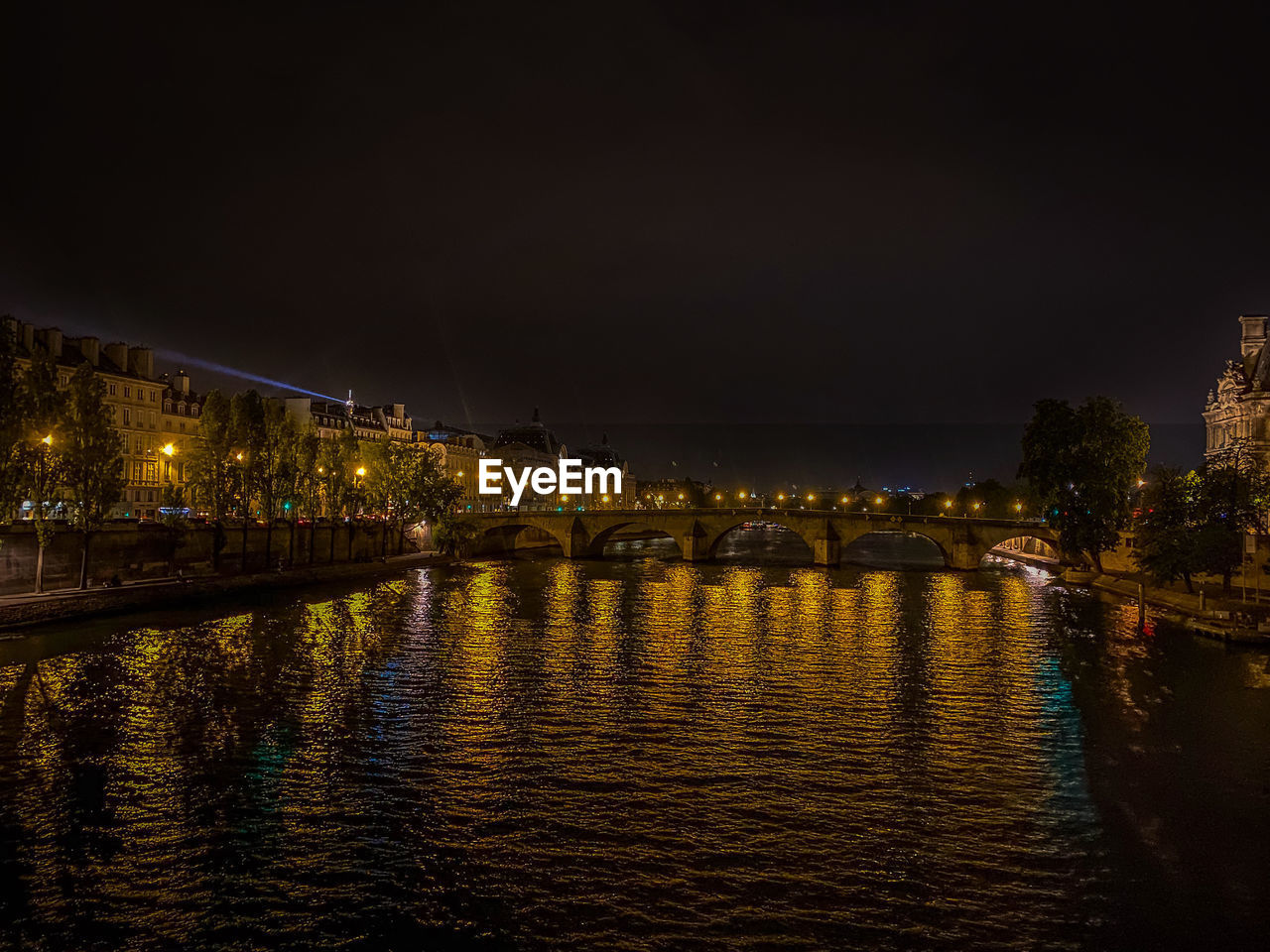 Illuminated bridge over river in city against sky at night