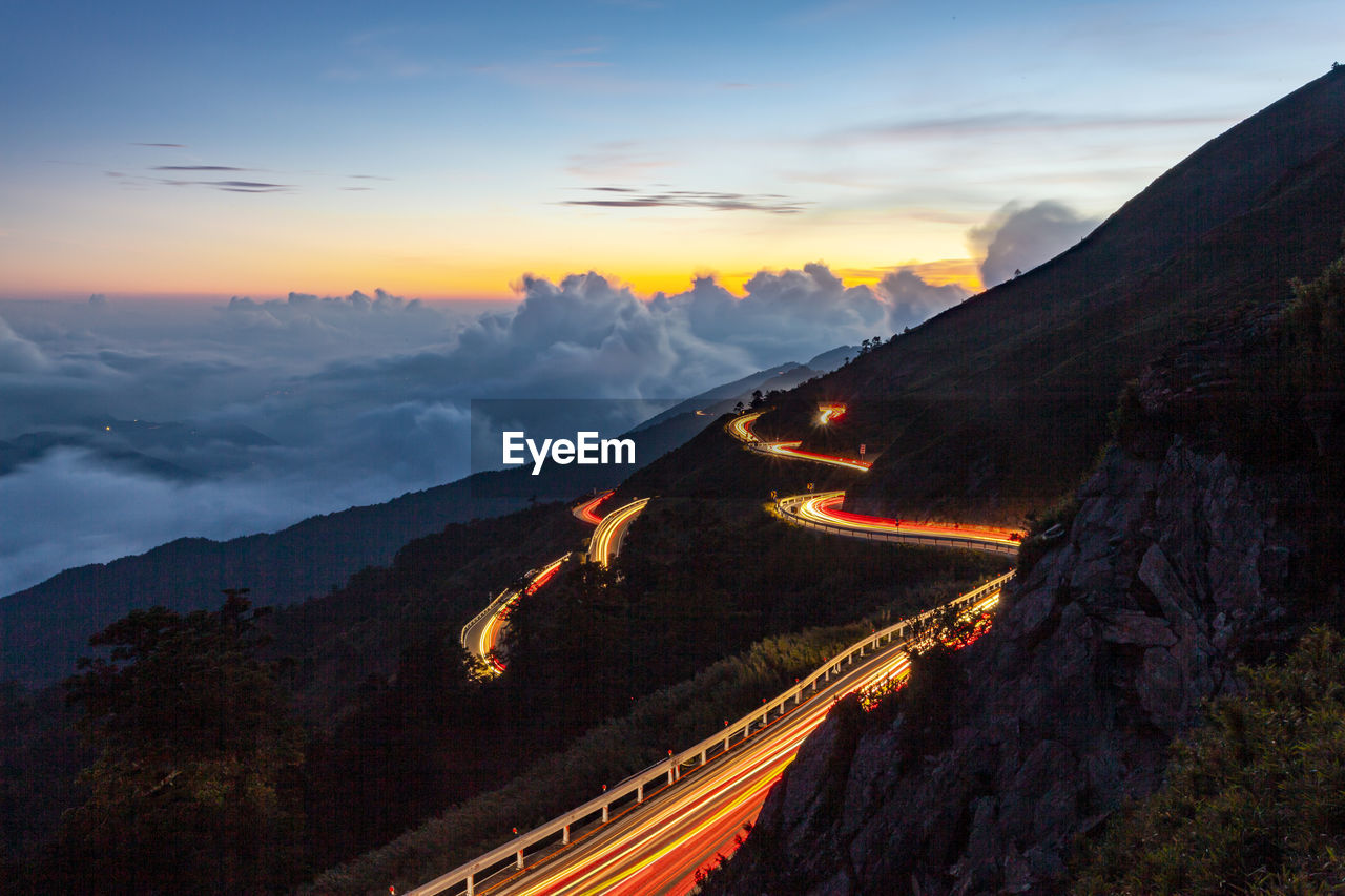 Light trails on road against sky during sunset