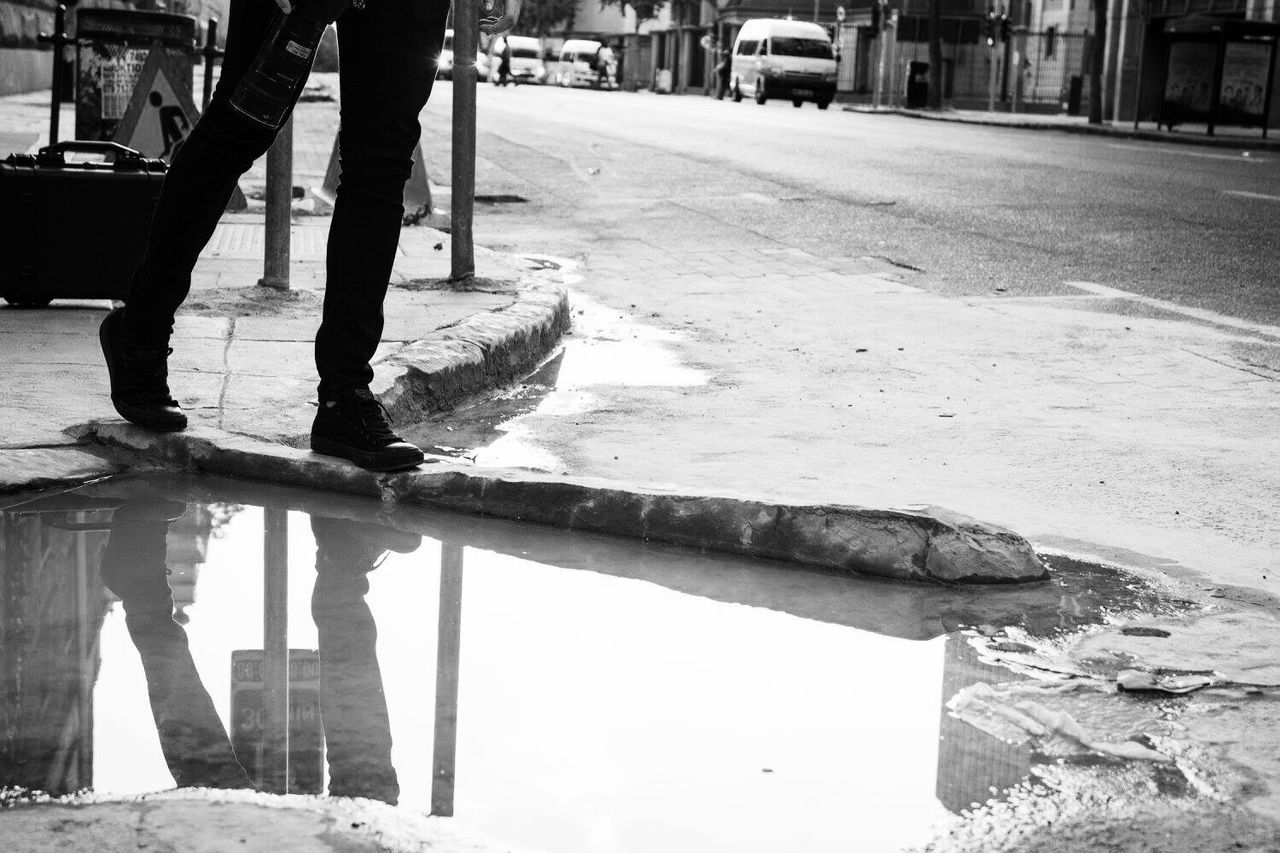 Low section of man reflecting on puddle
