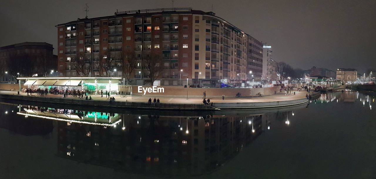 PANORAMIC VIEW OF ILLUMINATED BUILDINGS BY CANAL AT NIGHT