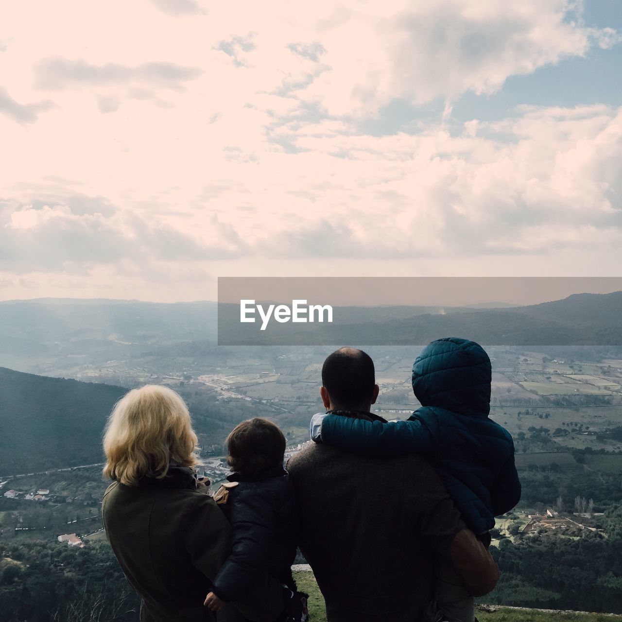 Rear view of a family looking at landscape from the top of a mountain