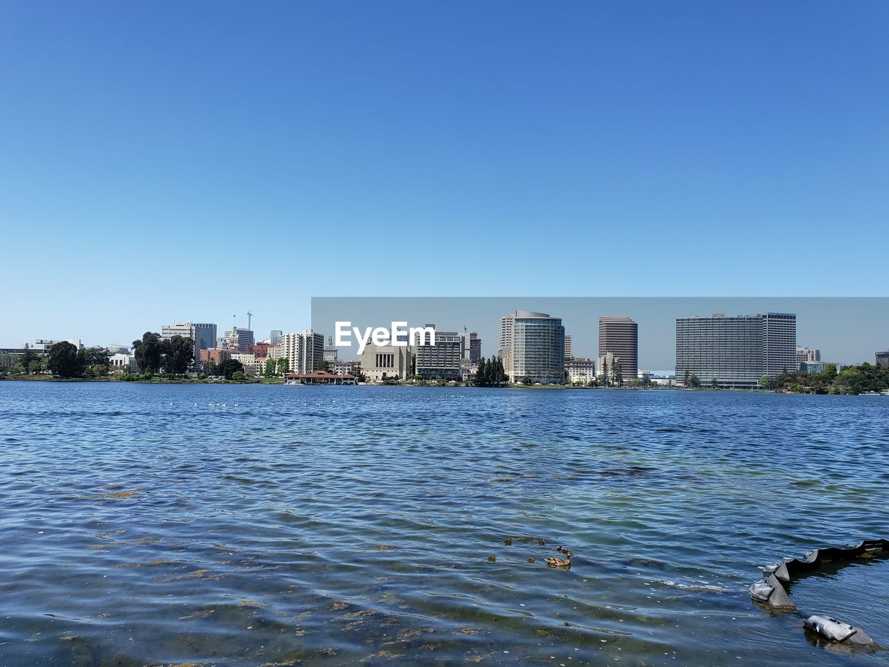 River and buildings against clear blue sky