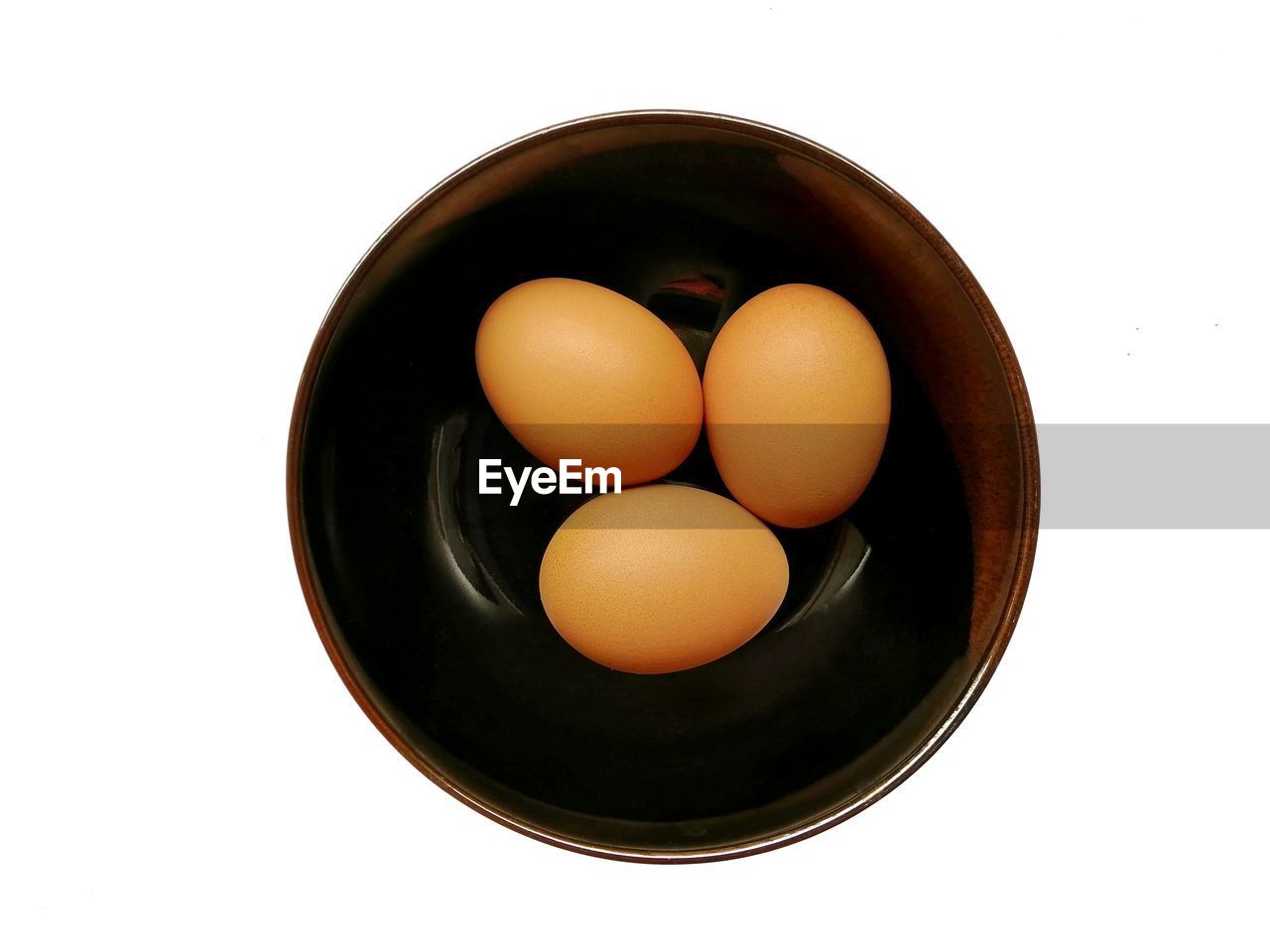 Eggs on black ceramic bowl isolated on whitebackground