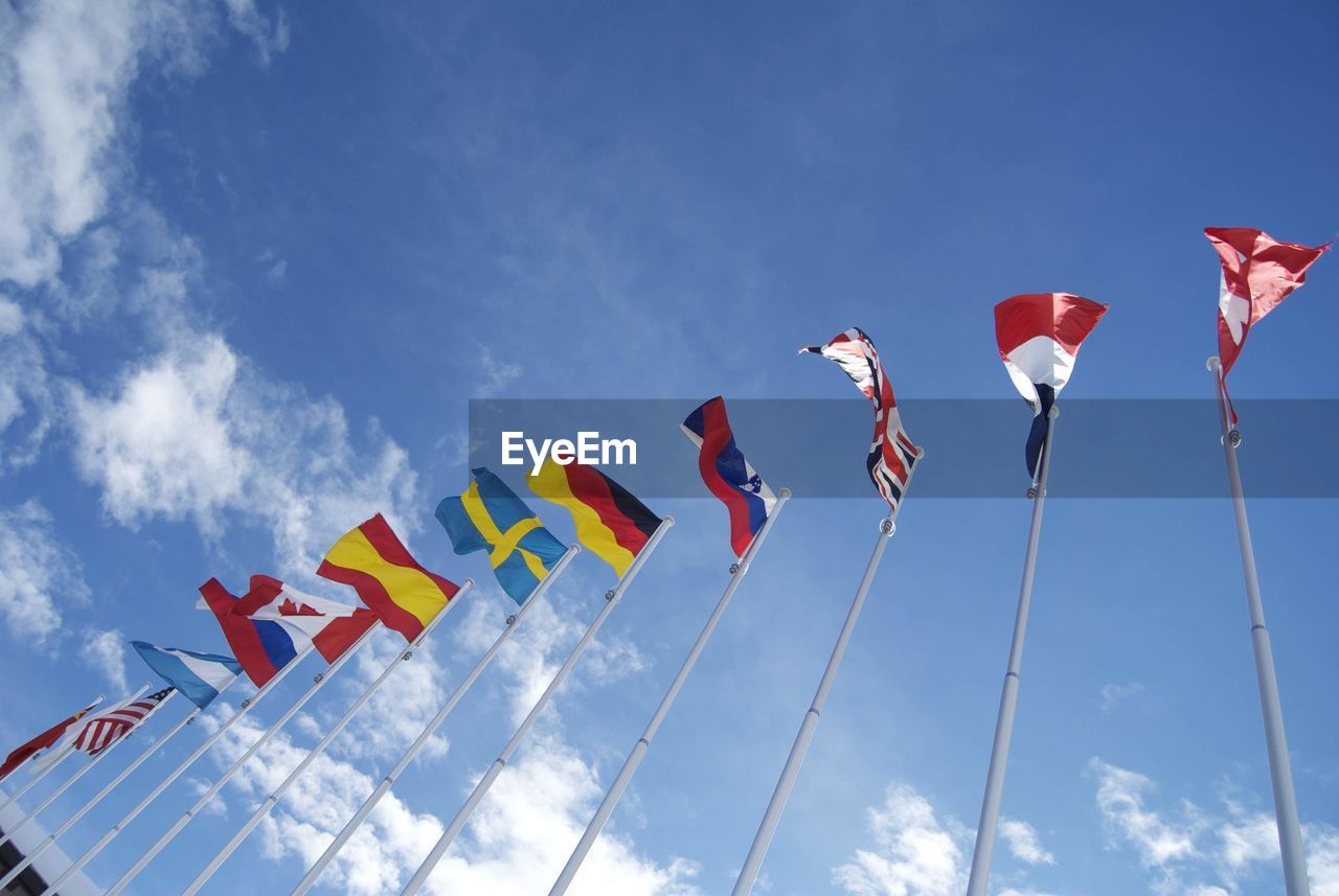 Low angle view of various flags against sky