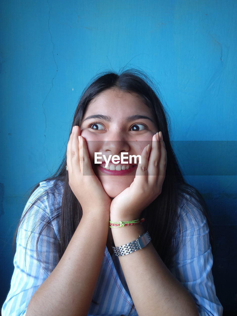 Close-up of smiling young woman sitting against wall