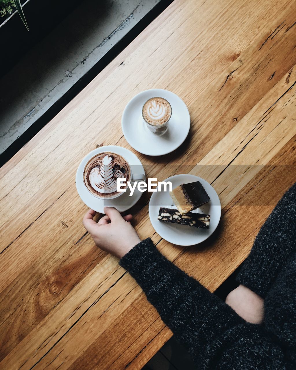 Cropped hand of woman holding coffee cup at table