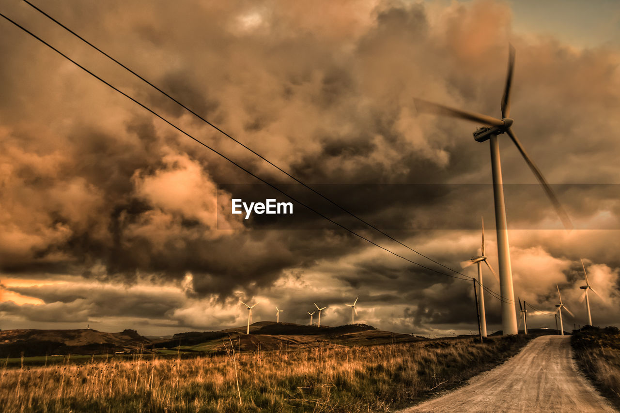 WIND TURBINES ON FIELD AGAINST SKY