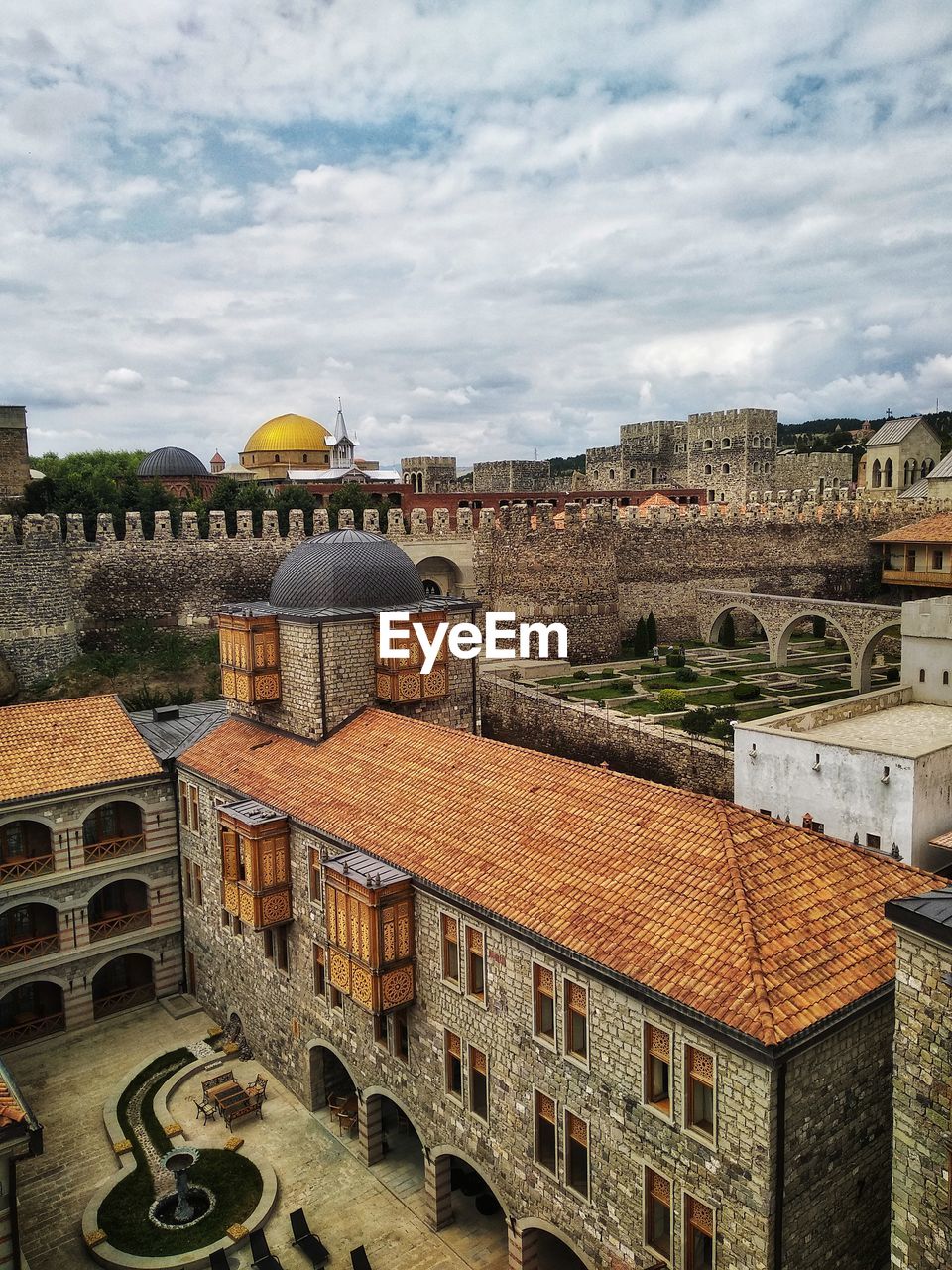 HIGH ANGLE VIEW OF CITY BUILDINGS AGAINST CLOUDY SKY